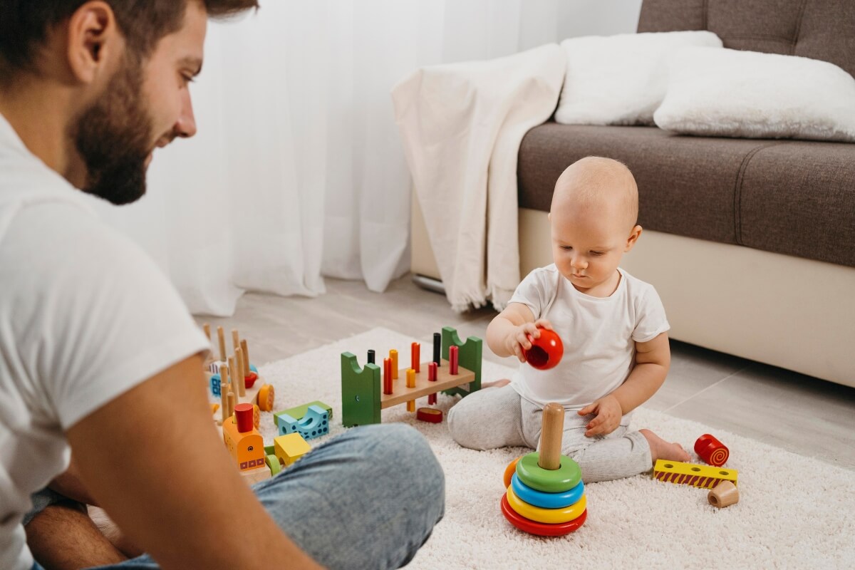 Father watching his baby playing with Montessori toys.