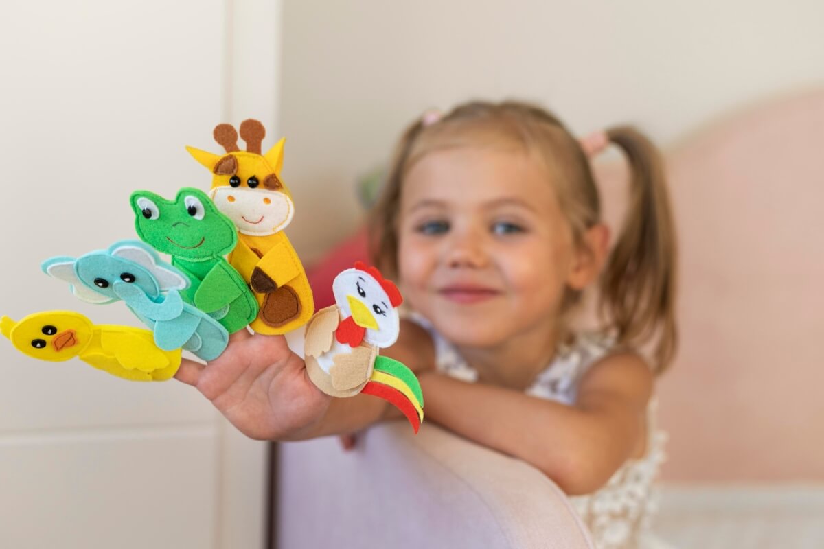 Little girl showing her felt animal toys. 