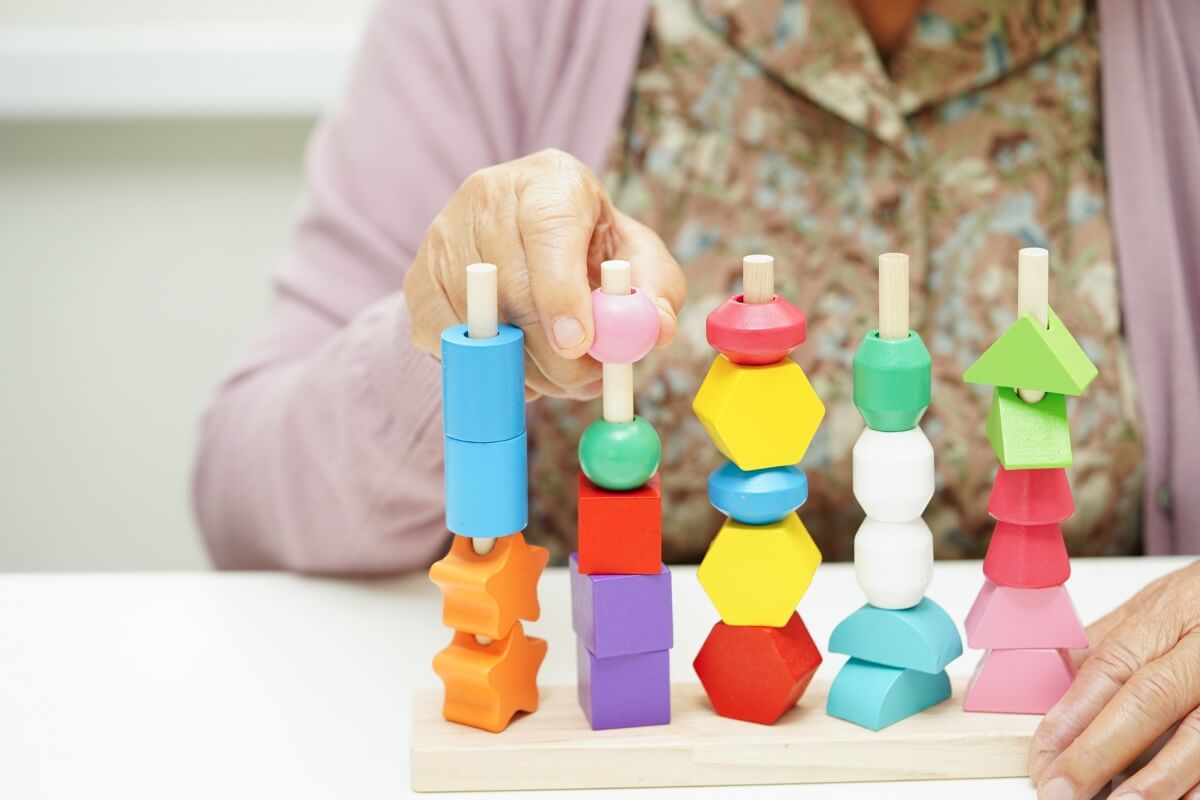 Montessori teacher evaluating and playing with a wooden Montessori stacking toy.