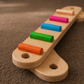 Wooden toy with colorful cylindrical beads that helps children learn and practice balance and movement coordination.
