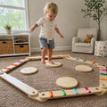 Little boy practicing his balance skills on a wooden Montessori floor toy with discs and beams.