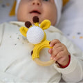 Baby holding a crochet giraffe on a wooden circle. 