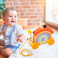 A baby sitting next to a wooden Montessori pulling toy.