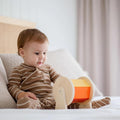 A sitting baby watching curiously at a spinning Montessori toy