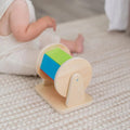Wooden Montessori spinning drum next to a baby.