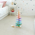 Wooden Montessori musical rainbow toy with marbles and leaves of different sizes placed on a bedroom floor.