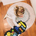 Little girl sitting on the carpet and playing with her Montessori Dino Busy Board