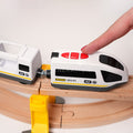 Child pressing the button on a toy train engine as it travels on a curved wooden track with a connected train car.