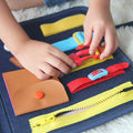 Child's hands closing a buckle in the Montessori Busy Board