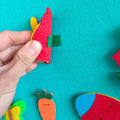 A hand putting an ornament to the Montessori Felt Bunny via the Velcro patch. 