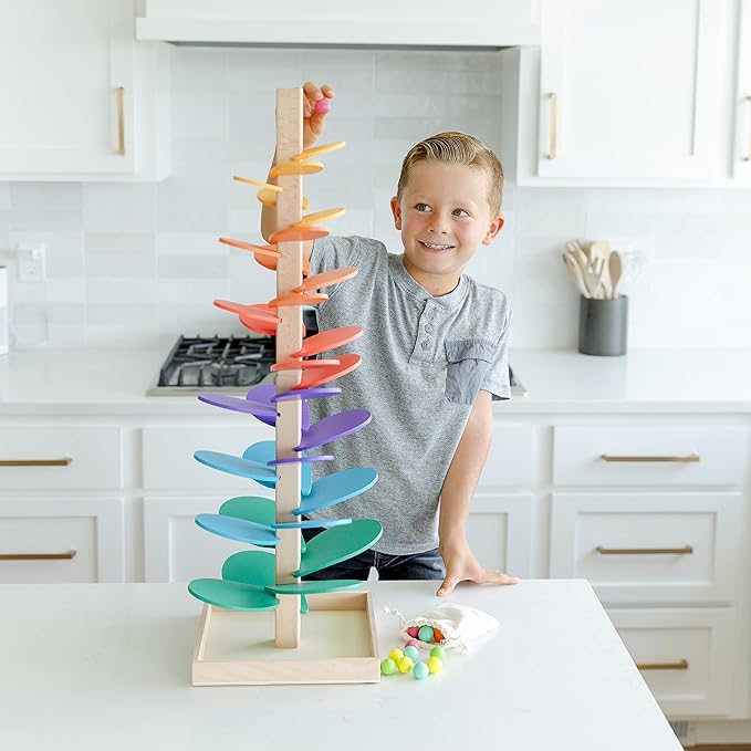 Little boy adding a wooden marble on top of the Montessori Rainbow Tree. 