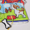 A page of the Montessori Baby Cloth Book with a picture of a dog and a bone attached to the book by the rope.