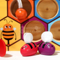 Closeup of the Montessori Bee Box's red and purple bees with a board behind them.