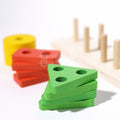 Close up of the green Montessori Building Blocks triangle piece, with other parts in the background. 