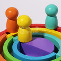 Wooden figurines sitting on top of the colorful Montessori rainbow.