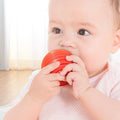A baby chewing on a Montessori Shape Blocks toy.