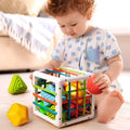 A baby playing with a Montessori Shape Blocks toy, trying to figure out how to fit all the pieces inside.