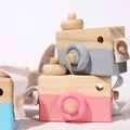 Grey Wooden Camera placed on top of the pink one with a small part of the blue camera in the left corner.