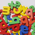 A pile of wooden letters on a white board that are a part of the Montessori spelling toy.